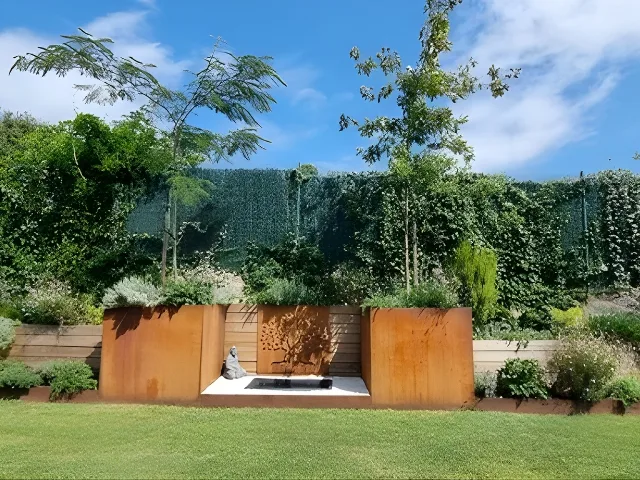 Jardinera de acero corten con árboles y zona central decorativa sobre césped.